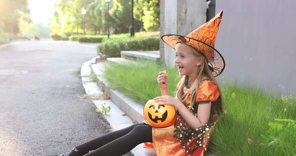 Cute Little Caucasian Girl with Blonde Hair Seven Years Old in Costume of Witch with Hat and Black