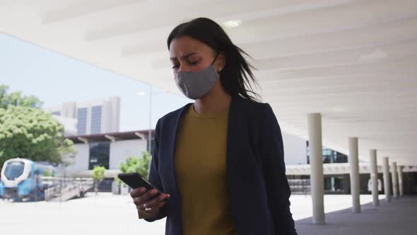 African american woman wearing face mask using smartphone