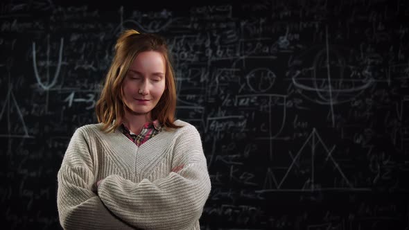 Portrait of Young Female Student Stands in Front of Blackboard with Mathematics Formulas