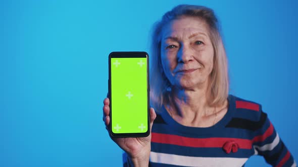 Old Woman Holding Smartphone with Green Screen and Nodding Head