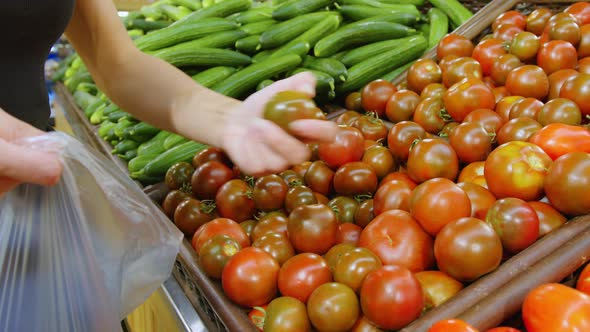 A Woman is Buying Tomatoes at the Supermarket