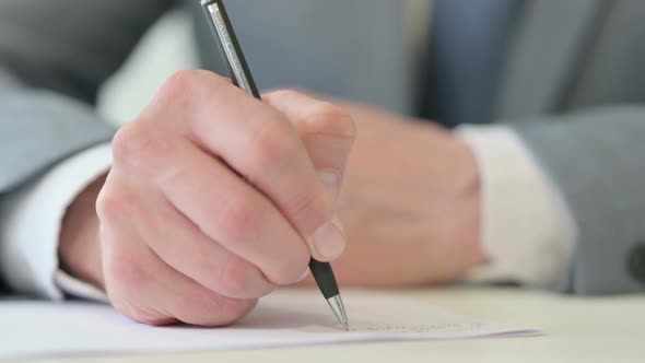 Close Up of Businessman Writing on Paper with Pen