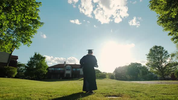 Rear View of the University Graduates Student at Silhouette Sunset Goes on the Road