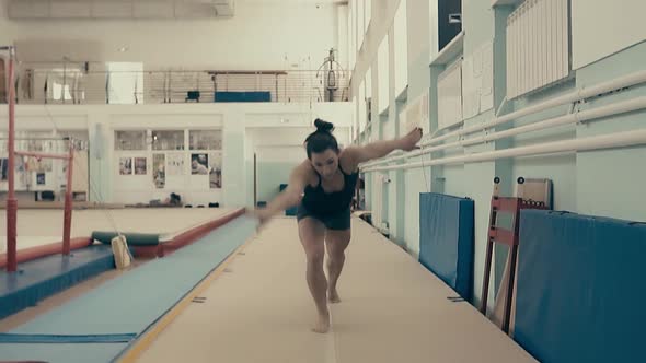 Female Athlete Exercising in the Gym Running Up and Doing a Double Somersault Back 3