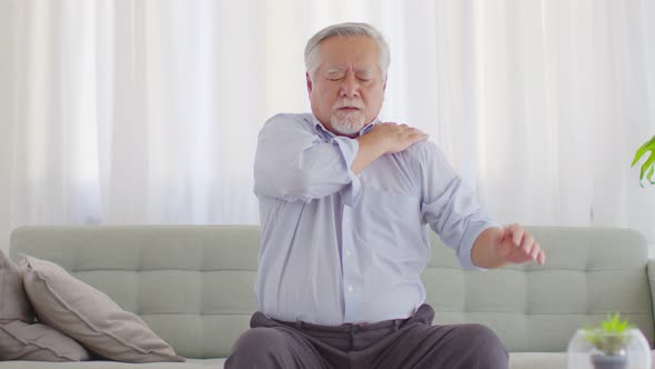 Asian Elderly senior man with white hairs shoulder pain and illness on sofa at home