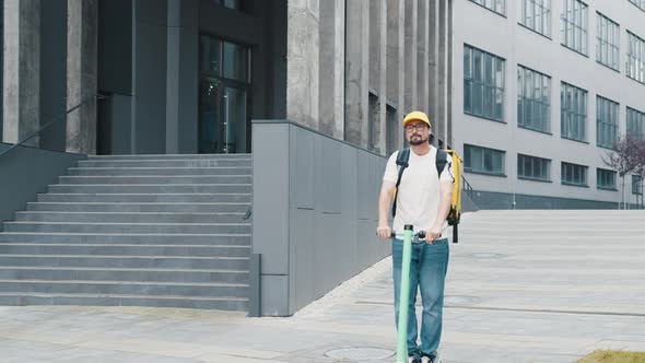 Smiling Man Courier Delivering Food with Yellow Thermal Backpack Rides Down the