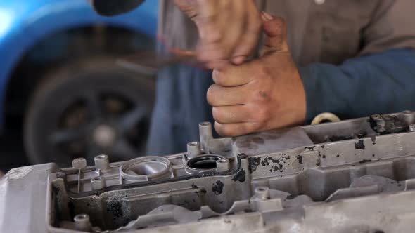 Closeup of a Mechanic with Dirty Hands Repairing the Engine From the Car