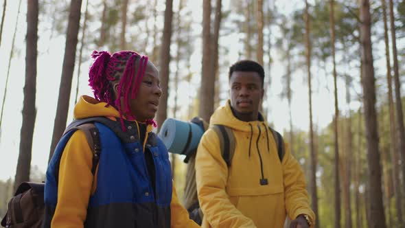 A Young Couple of Black Men and Women Walk in the Woods During a Trip to the Woods with Backpacks in