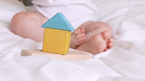 eco wood toys at baby feet. Little clever caucasian child playing with natural wooden toys on bed