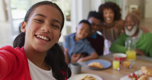 African american girl taking a selfie while having breakfast with her family at home