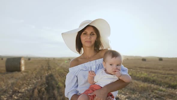 Young Woman in a Dress with a Big Hat and Her Little Son