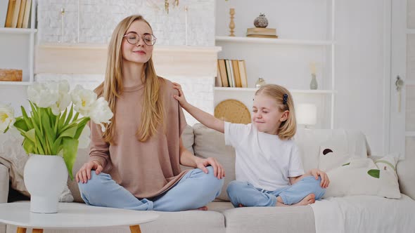 Caucasian Family Young Calm Mother Woman Blonde Meditates with Toddler Girl Child Daughter Sit in