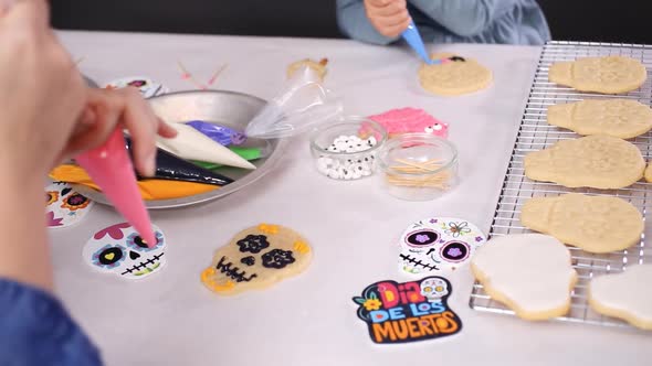 Step by step. Mother and daughter decorating sugar skull cookies with royal icing for Dia de los Mue