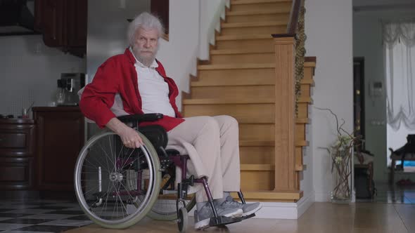 Old Disabled Bearded Caucasian Man Looking Up at Stairs and Rolling Wheelchair Away in Slow Motion