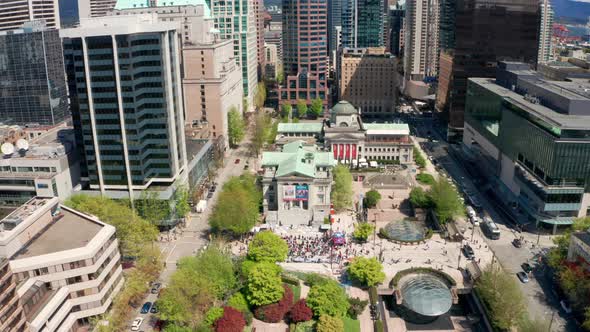 Aerial overhead view of a political anti-vaccine rally in a downtown city among huge skyscrapers. Ti