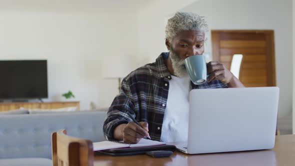 Senior man drinking coffee while taking notes