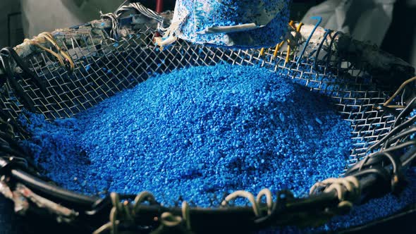 Blue Plastic Particles Raining Down Into a Bowl