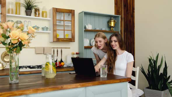 Two Students Using Video Chat Online On Laptop To Contact Friends, Talking And Laughing