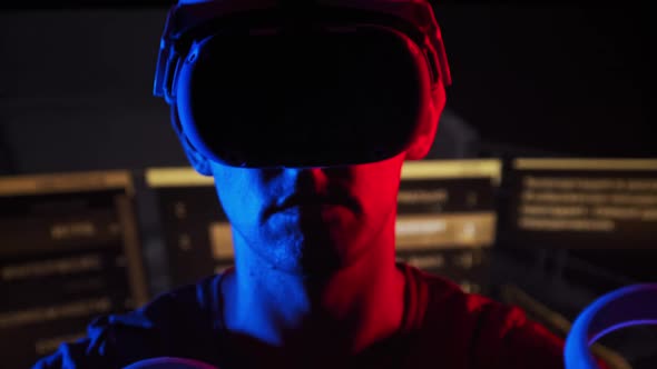 Man in a Virtual Reality Helmet Illuminated in Red and Blue Plays a Game