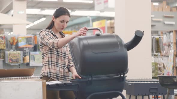 Portrait of a Girl in a Plaid Shirt Looking at a Grill in a Shop