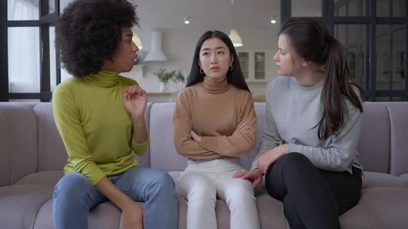 Wide Shot Portrait of Sad Brokenhearted Beautiful Asian Woman Sitting on Couch As African American