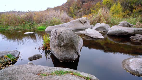 A Fast Clean Stream Runs Among Smooth Wet Stones Surrounded By Tall Dry Lumps