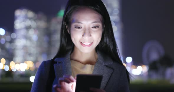 Woman look at mobile phone in city at night