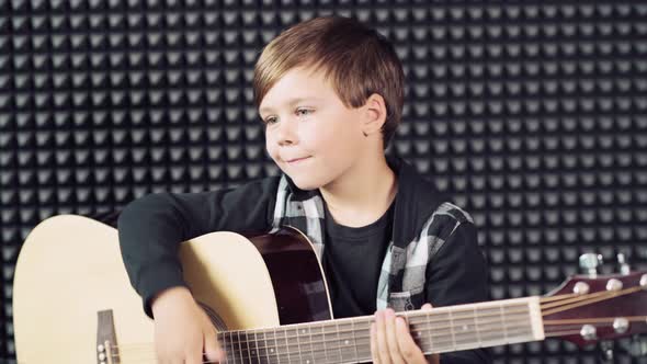 Cute Handsome Brunette Boy Plays the Guitar and Looks at the Camera.