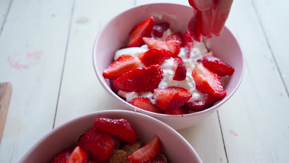 Close Up Putting Cutted Strawberry in to Bowl with Berries Yogurt and Flakes