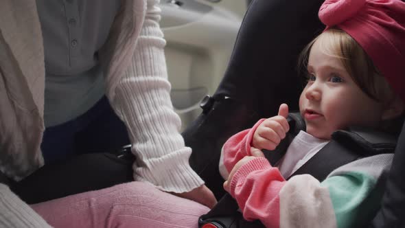 Mid section of caucasian mother keeping her baby in safety seat in the car