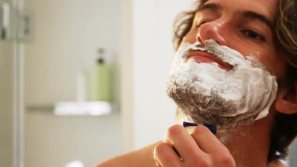 Man using a razor to shave his beard off