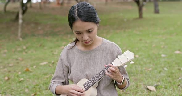 Woman enjoy play ukulele and song in the park