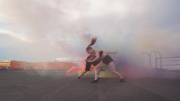 Slow Motion Female and Man Doing a Somersaults Multi Colored Smoke Bombs on a Background Gymnastic