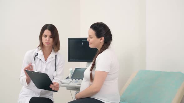 Gynecologist with Clipboard Talking with Pregnant Woman