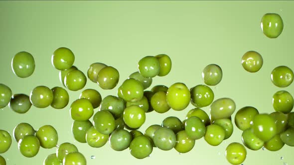 Super Slow Motion Shot of Flying Fresh Green Olives on Light Green Gradient Background at 1000 Fps