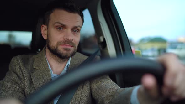 Satisfied Bearded Man Driving a Car Down the Street in Sunny Weather