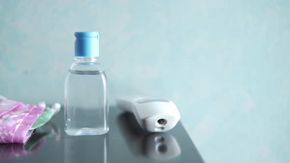 Surgical Masks Thermometer and Hand Sanitizer on Table