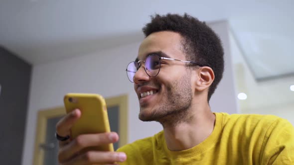 Happy African Man Using Smart Phone at Home