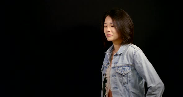 Pretty Chinese Woman Is Wearing Denim Jacket Is Smiling, Standing in Black Background