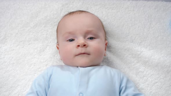 Portrait of Cute Baby with Blue Eyes Lying and Smiling in Camera