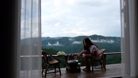 A woman cooking and eating Moo Kata, Thai barbecue grill pork