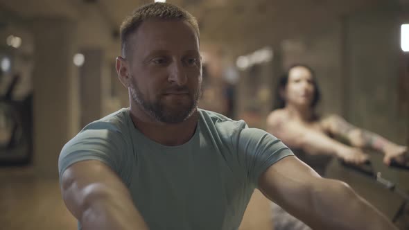 Confident Adult Caucasian Man Stretching Resistance Bands and Smiling. Bearded Handsome Sportsman