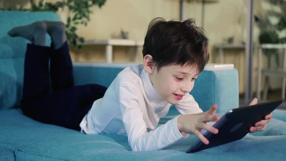 Small Kid Hold Pad Computer Surfing Internet Play Game At Home Alone.