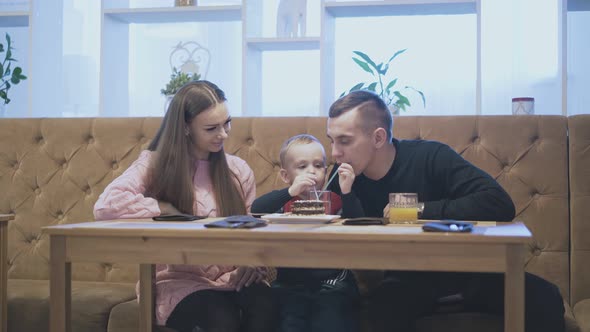 Lucky Smiling Parents Play with Small Son Sitting on Sofa