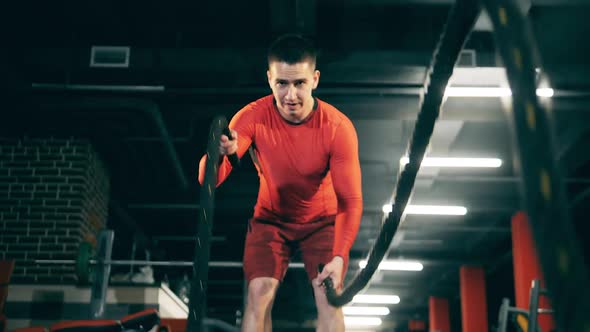 A Sportsman Wokouts in Gym with Battle Ropes