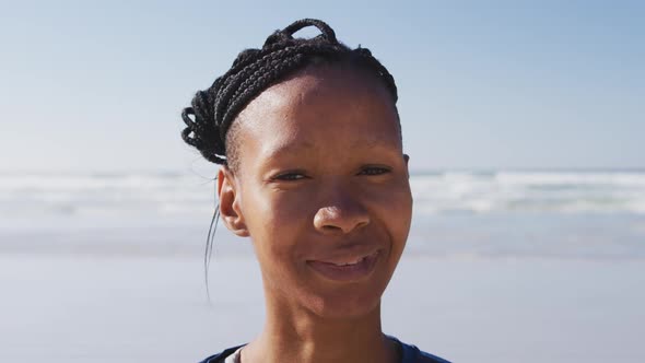 African American woman looking at camera and smiling on the beach and blue sky background