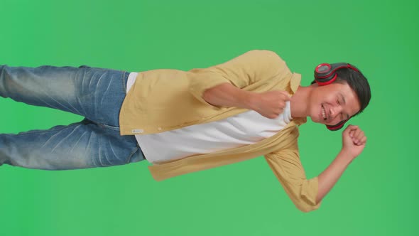 Asian Man Listening To Music With Headphones And Dancing In The Green Screen Studio