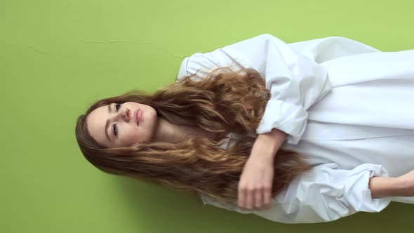 Pretty Girl With Long Hair Stands Near The Wall.