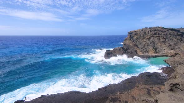 Blue Pacific Ocean waves hitting at volcanic rocks of shore at Hawaiian island Oahu.