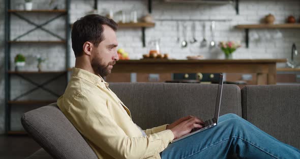 Young Man Freelancer Using Laptop Device While Resting on Sofa at Home Portrait of Male Working